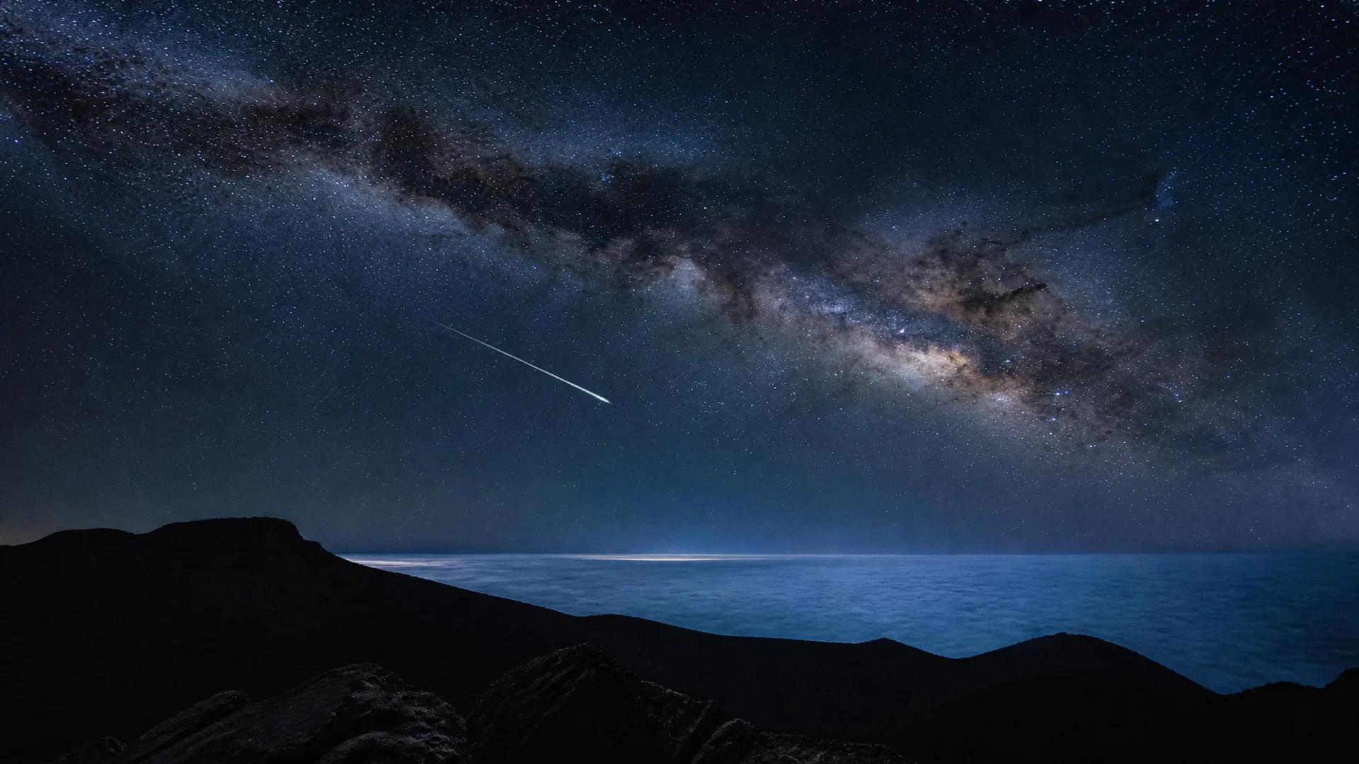 A shooting star crossing the Milky Way over the summit